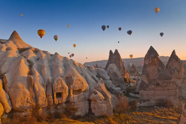 Hot-air balloons rising over fairy chimneys at sunrise in Cappadocia