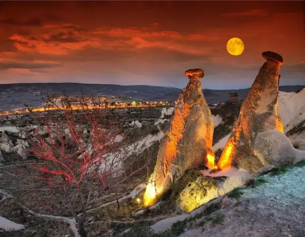 Fairy chimneys near Ürgüp lit at night under a full moon